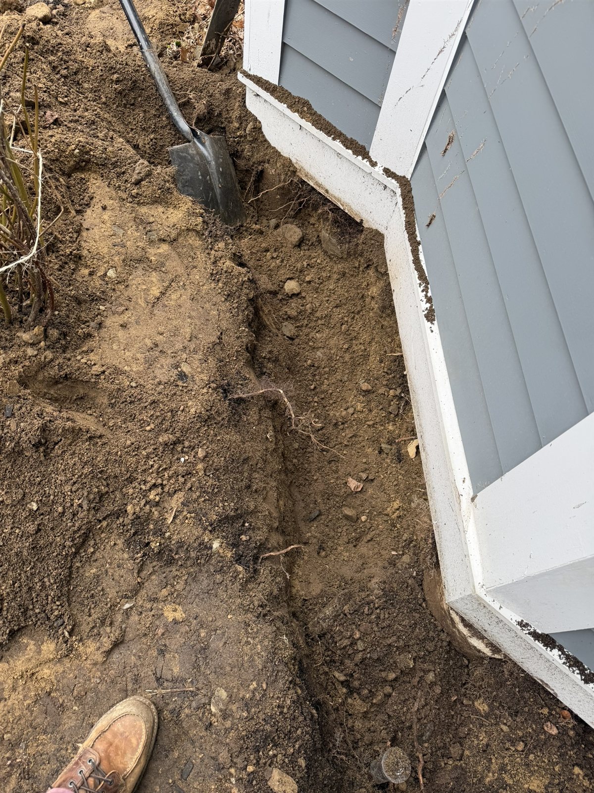 Excavated trench along the foundation of a house, before exclusion hardware is installed.